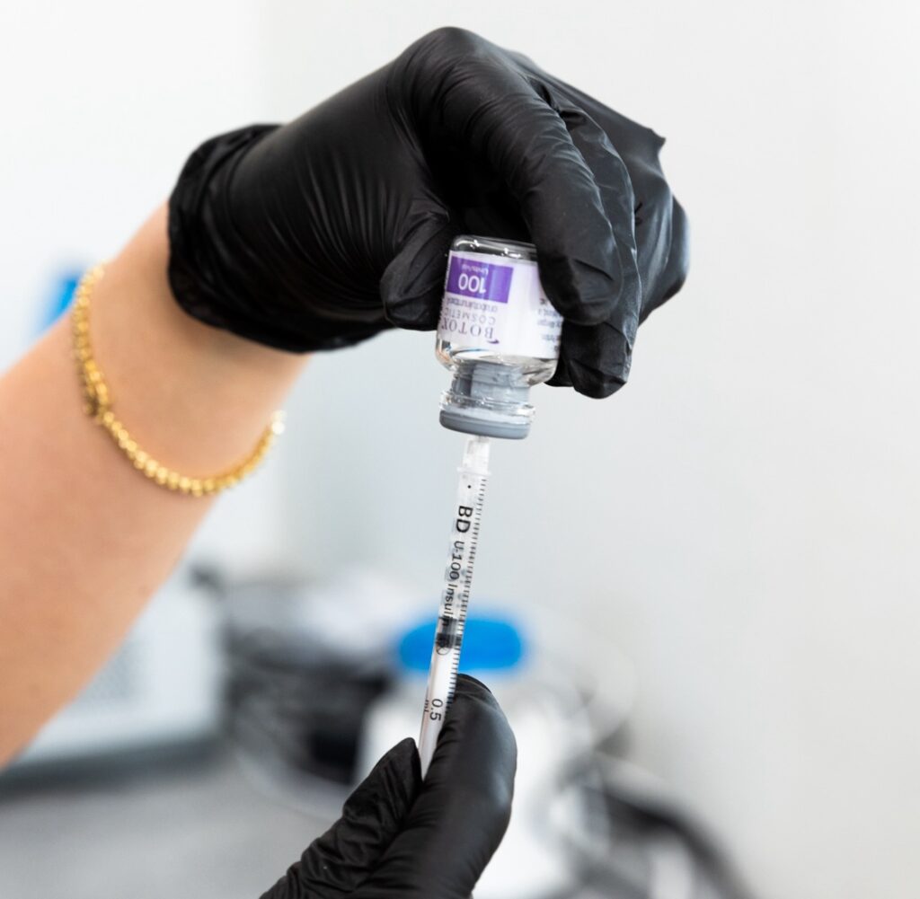 A provider with gloves prepares a treatment for facial balancing near Hayden