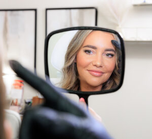 A woman holds up a mirror after Botox near Hayden.