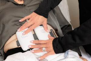 A patient lies back and receives body contouring near Hayden.