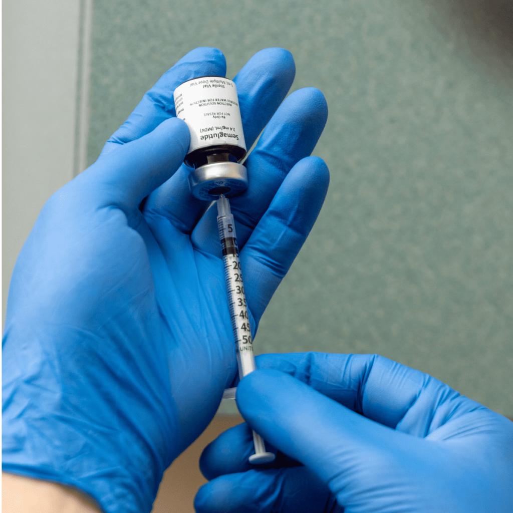 A close-up of two latex gloves preparing a vial of GLP-1 near Hayden.