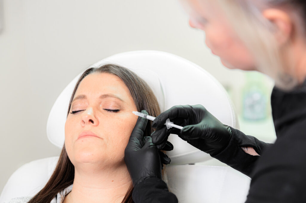 A woman with long hair closes her eyes while a provider injects Botox and fillers in Coeur d’Alene.