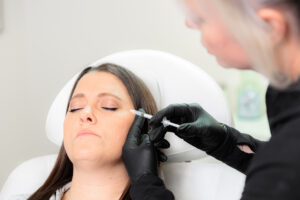 A woman receives an injection in the side of the face for facial balancing near Hayden