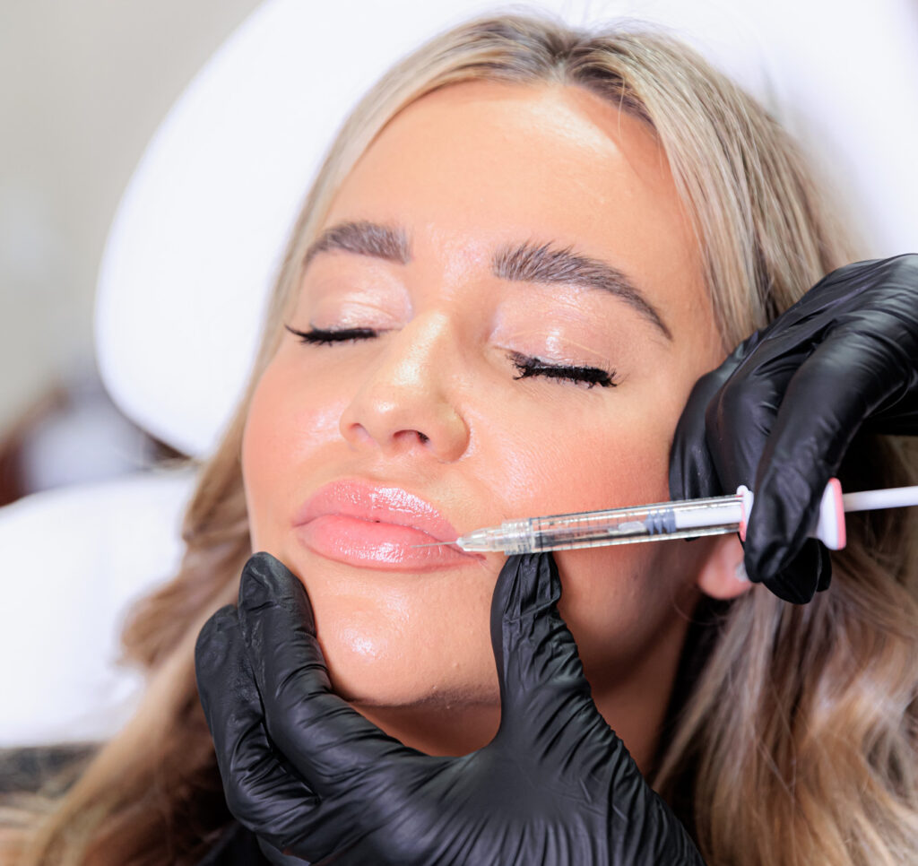 A woman shuts her eyes as she receives lip fillers near Hayden.